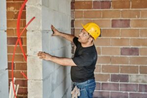 A man with a safety helmet holding a wall